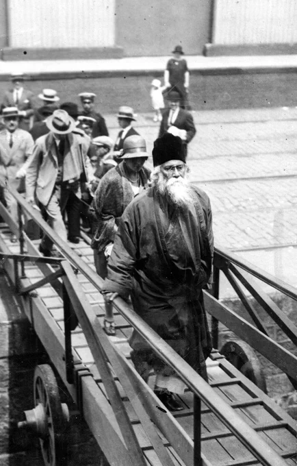 Black and white historical photo of a group of people boarding a ship, with Rabindranath Tagore in the foreground.