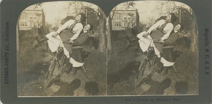 From the Mississippi State University Libraries Frank and Virginia Williams Collection of Lincolniana. Stereograph titled "A Lesson on Brother's Bike." The stereograph is a black and white image of a woman on a bike with another woman supporting the bike. The image is on a gray card mount.