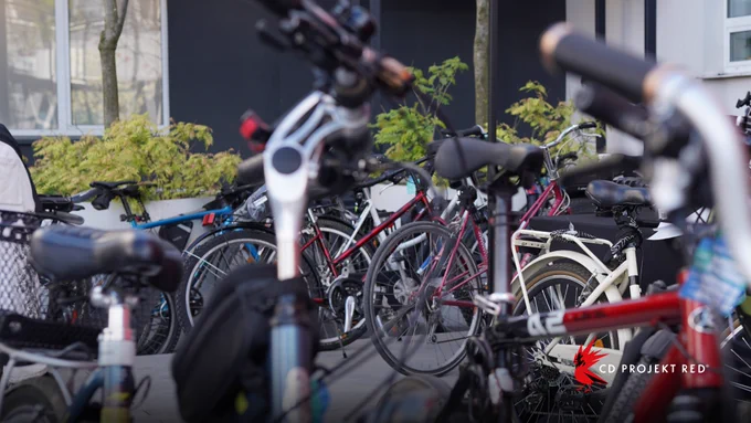 Several push bikes lined up outside the entrance to the CD Projekt Red Headquarters in Warsaw. The CD Projekt Red logo is printed in the bottom right corner of the image.