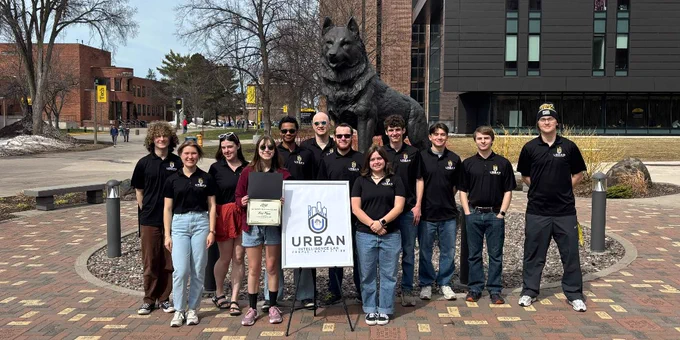 Members of the Urban Intelligence Lab Enterprise stand together in front of the Husky statue on Michigan Tech’s campus. 
