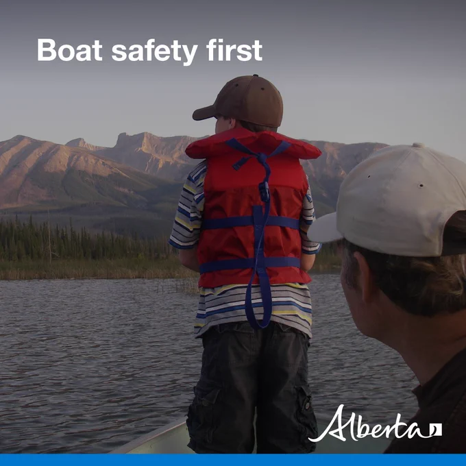 image depicts a small child wearing a life jacket at the bow of a boat on a mountain lake. Text reads Boat safety first with the white Alberta logo in the bottom right corner.