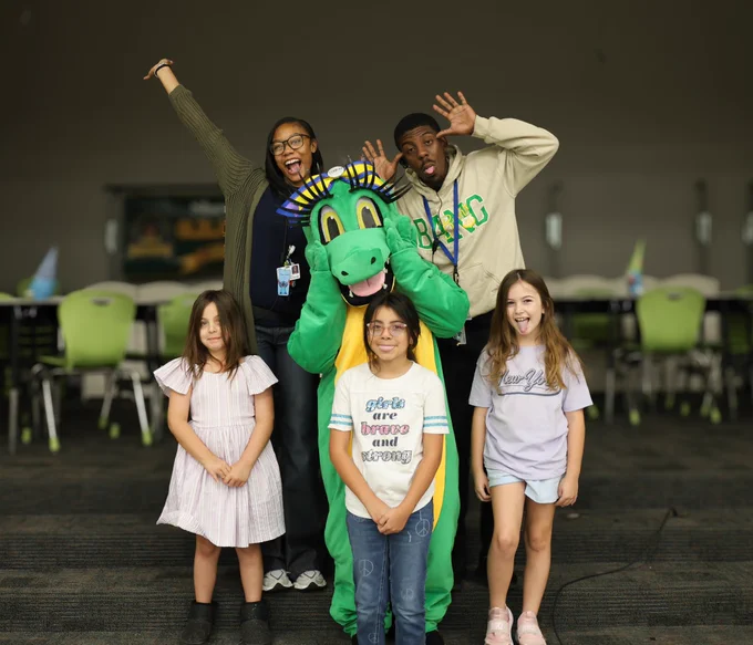Allie the Alligator is making a silly face with Club Rewind students and leaders.