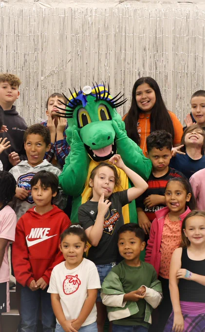 Allie the Alligator is making silly faces with a large group of Club Rewind students.