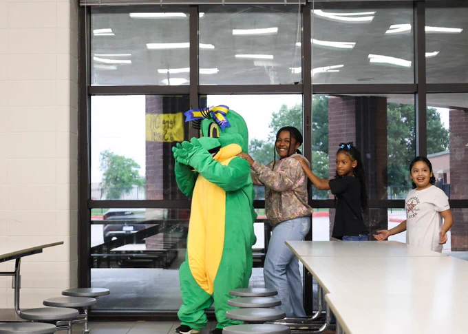 Allie the Alligator is leading the way in a Conga line with Club Rewind students following her.