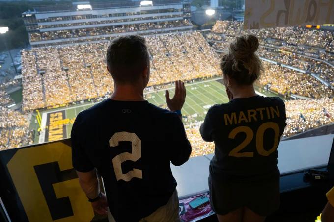 Two people waving from the windows of the Children's hospital.
