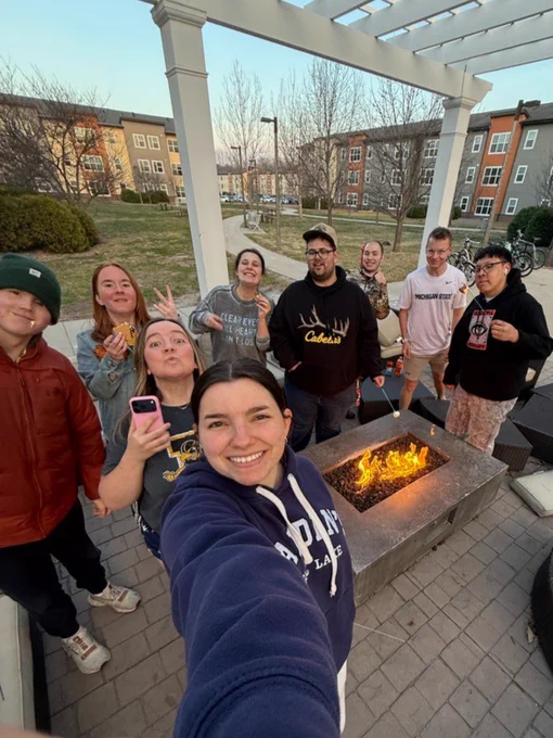 A UI REACH mentor and students stand around a bonfire making s'mores.