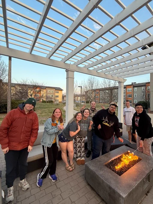A UI REACH mentor and students stand around a bonfire making s'mores.
