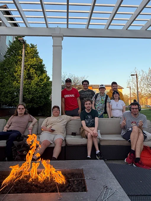 A UI REACH mentor and students stand around a bonfire making s'mores.