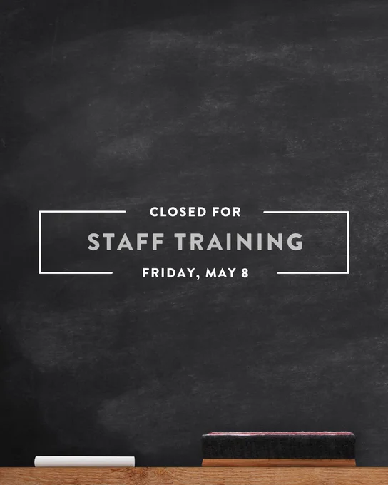 Chalkboard with the text "Closed for Staff Training, Friday, May 8" in white letters. An eraser and a piece of chalk are on a wooden ledge at the bottom.