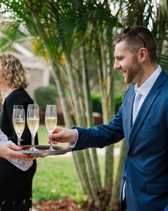 A photo of a man grabbing a glass of champagne from a server tray at a wedding ceremony at Innisbrook Resort in Palm Harbor, FL.