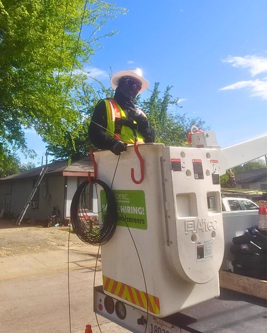 Sonic team member posing while in the bucket of a bucket truck in Dallas before completing the fiber drop for a new Sonic member 