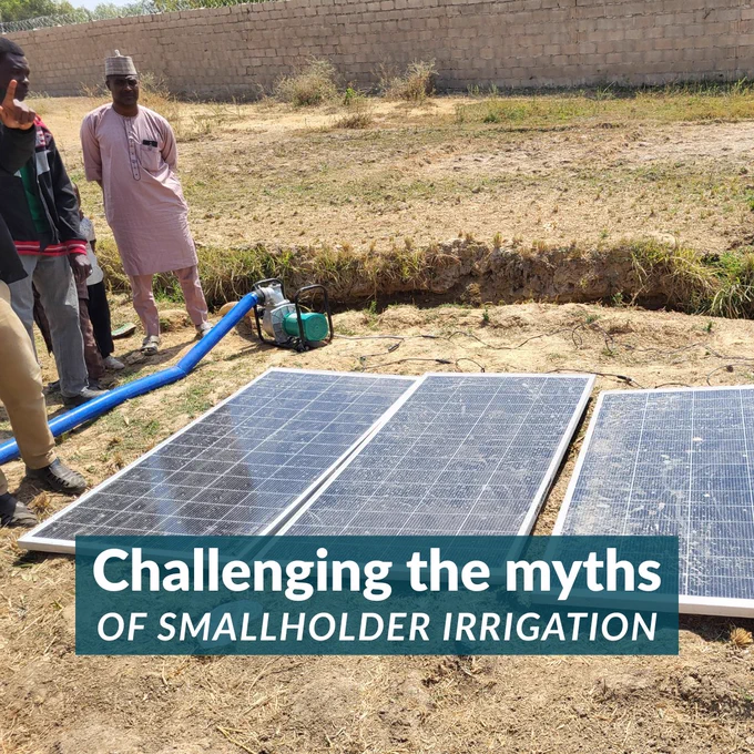 Group of men standing near solar panels powering an irrigation pump in a dry field.