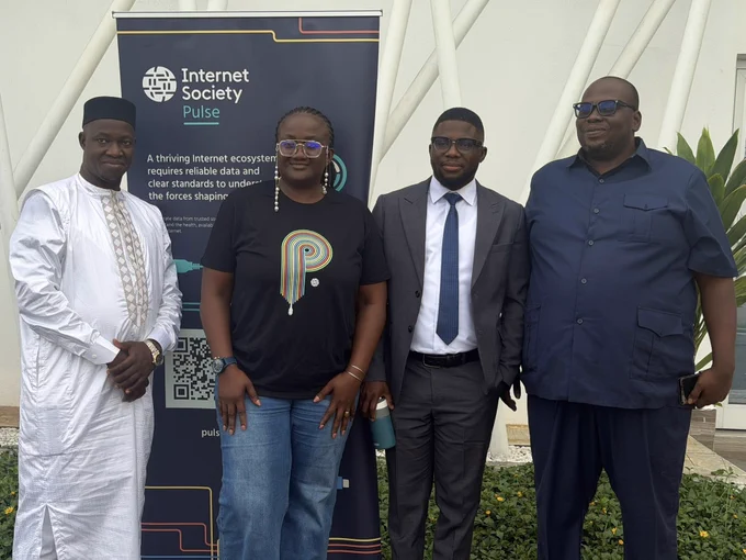 Four people stand next to an Internet Society Pulse sign at an Internet Measurement Fourm