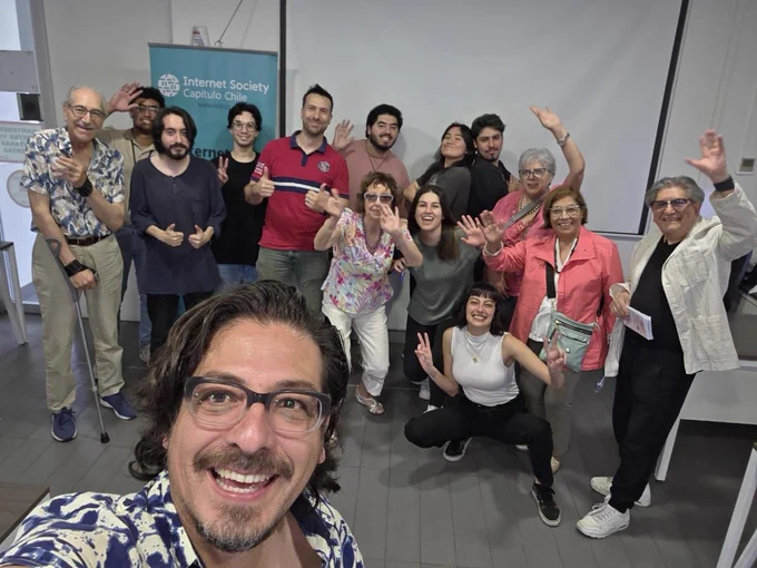 A man takes a selfie with a group of people standing behind him.