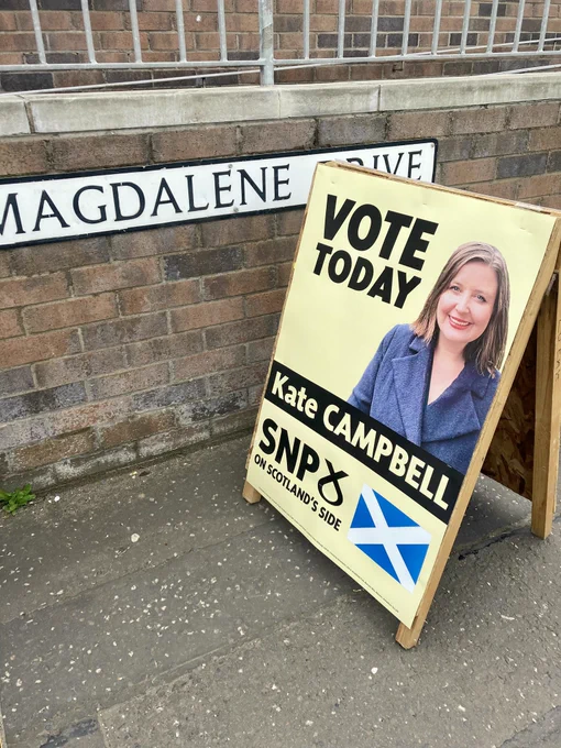 An SNP A board,  outside a polling station with a street sign behind which says Magdalene Drive.