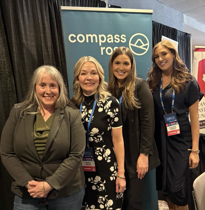 Four women posing for a photo in front of a corporate banner. 