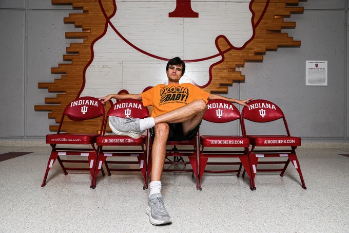 A person sits in a chair positioned in between four other chairs.