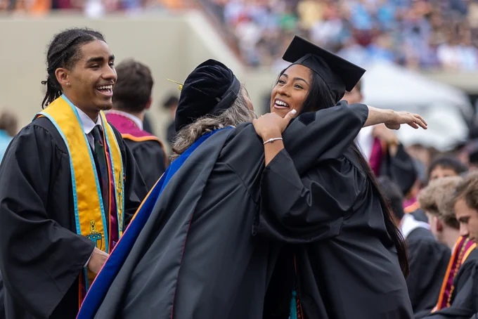 graduate hugging professor at commencement 