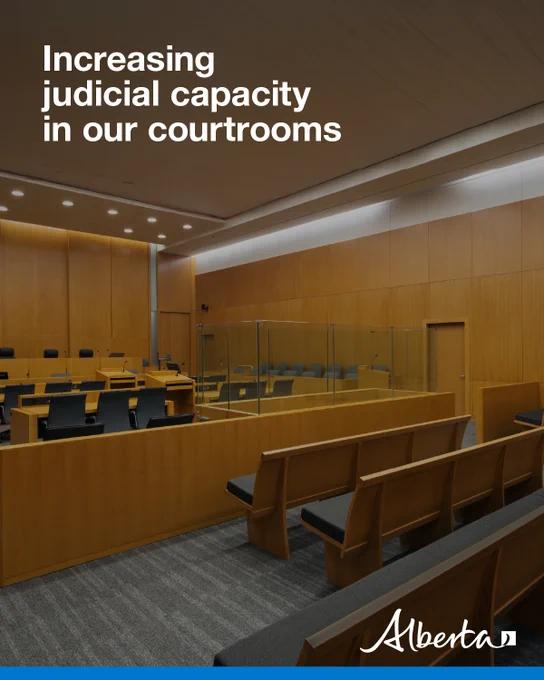Empty courtroom viewed from the public seating, with wood paneling and the judge’s bench; overlaid text reads ‘Increasing judicial capacity in our courtrooms.’ The Government of Alberta logo is on the bottom right.