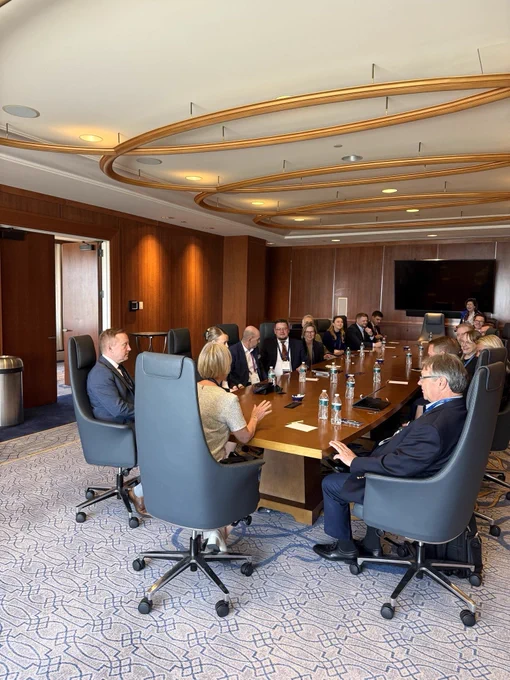 Ambassador and delegation sitting around a table speaking.