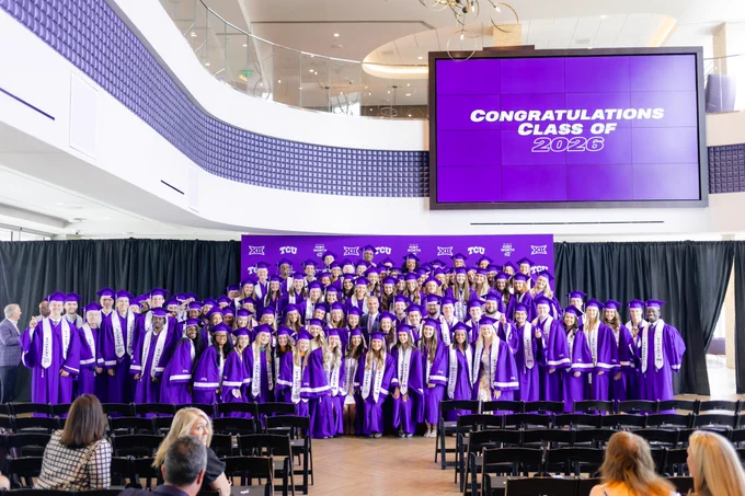 TCU AD Mike Buddie in a photo with 2026 TCU Student-Athletes Graduates, standing on a stage with a background graphic, "congratulations class of 2026" 