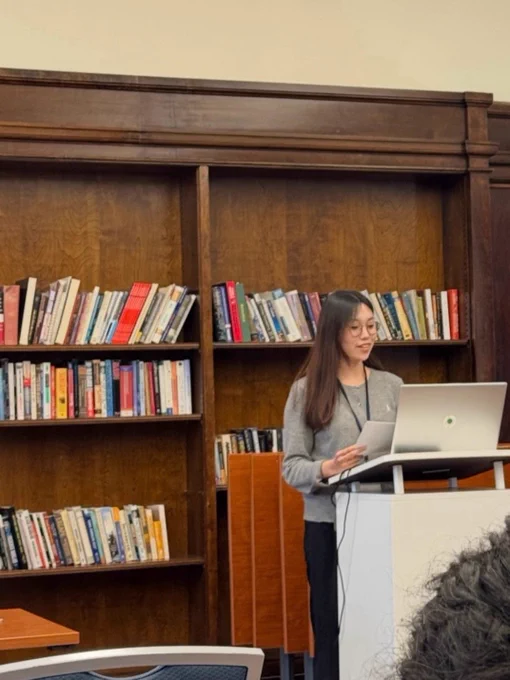 Seyoung Kim presents her research at a lectern in a library.