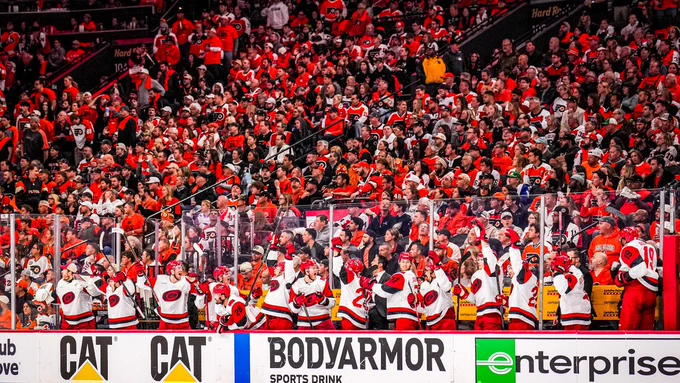 Photo of the Canes celebrating on the bench with Flyers fans sitting quietly in their seats