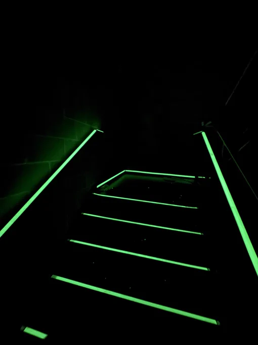 Photo of glowing stairwell stair and handrail nosings during actual loss of power event on installation day at Theory Madison in Madison, Wisconsin, USA. Stairwell glow markings installed by Luminous Egress for Mortenson Construction.