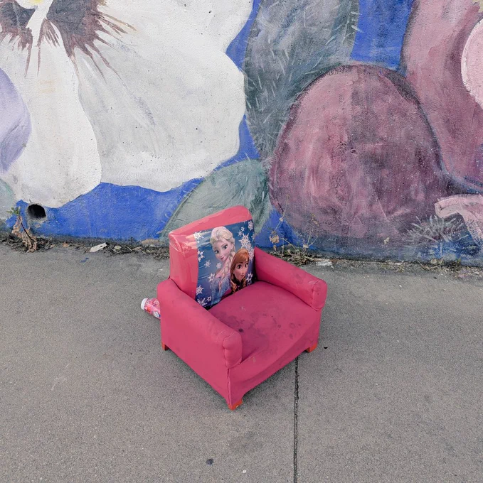 This is a pink Delta Children Disney Frozen II Upholstered Chair. in front of a mural of flowers and cacti. 
