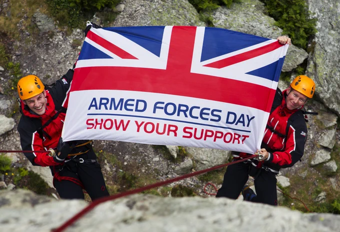 Personnel hold an Armed Forces Day flag reading 'show your support'.