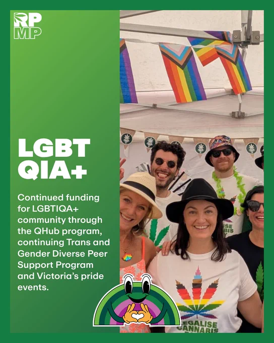 A group of people smiling under rainbow flags at a pride event, emphasizing community and support for LGBTQIA  programs.