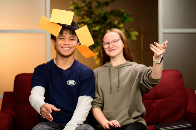 Two out of focus students behind some notecards that they have thrown in the air.