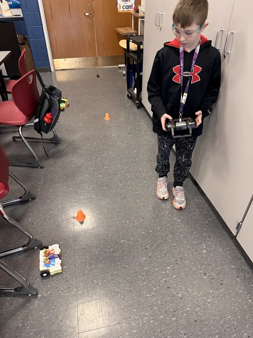 A student drives their BattleBot around the classroom. 
