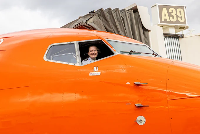 The pilot looks out of the cockpit window of a Sun Country airplane.