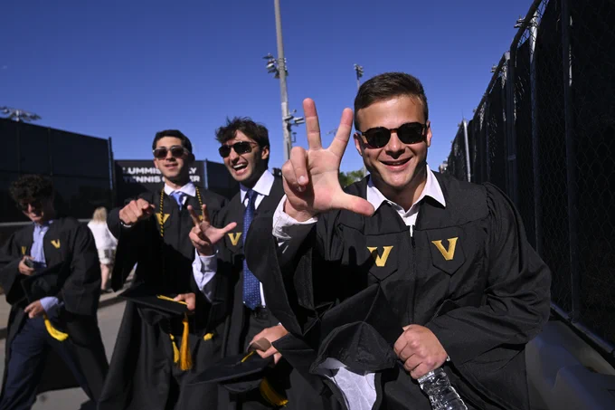 Graduates wearing caps and gowns smile for a photo ahead of Commencement. 