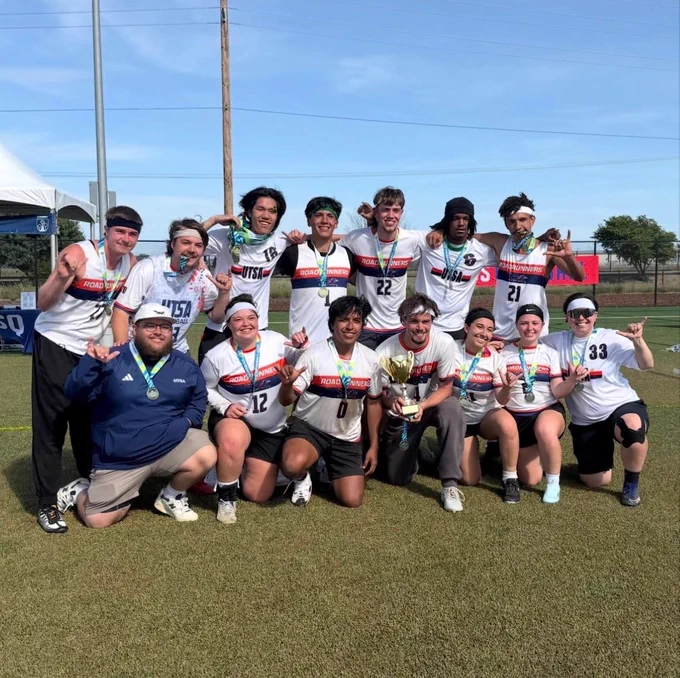 Quadball players in their uniforms with their medals and a trophy, smiling.