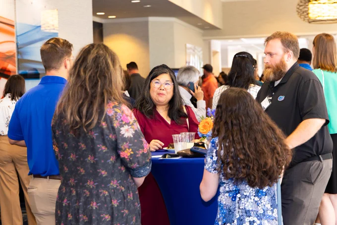 Faculty and staff mingling around a table.