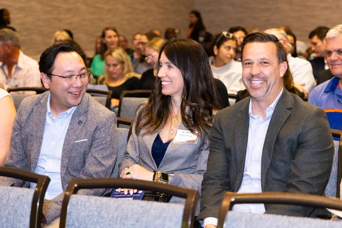 Faculty and staff smiling and laughing while sitting in rows.
