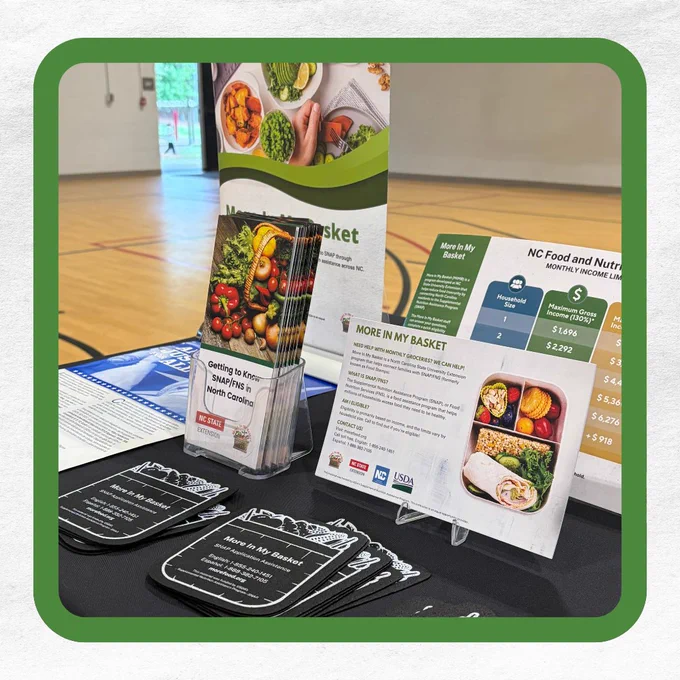 Display of informational materials about the SNAP and MIMB programs on a table in a gymnasium.