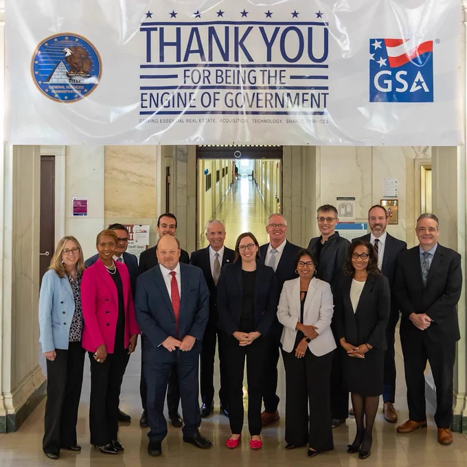 Group of professionals standing under a banner thanking government workers for their essential roles in real estate and technology.