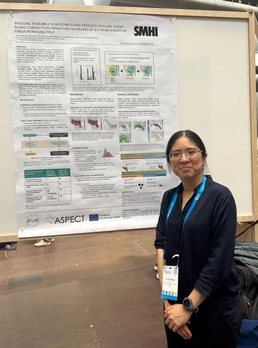 Conference delegate standing beside a scientific poster on extreme weather modelling, with charts, maps and text blocks visible on the board.