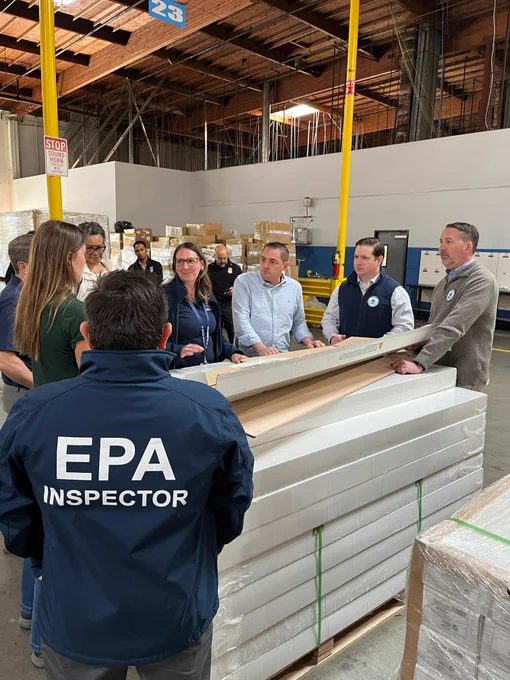 EPA inspectors demonstrating a review of composite wood flooring to ensure products meet labeling requirements, allowing EPA to verify flooring has undergone testing for formaldehyde emissions, with EPA senior leaders at port warehouse.