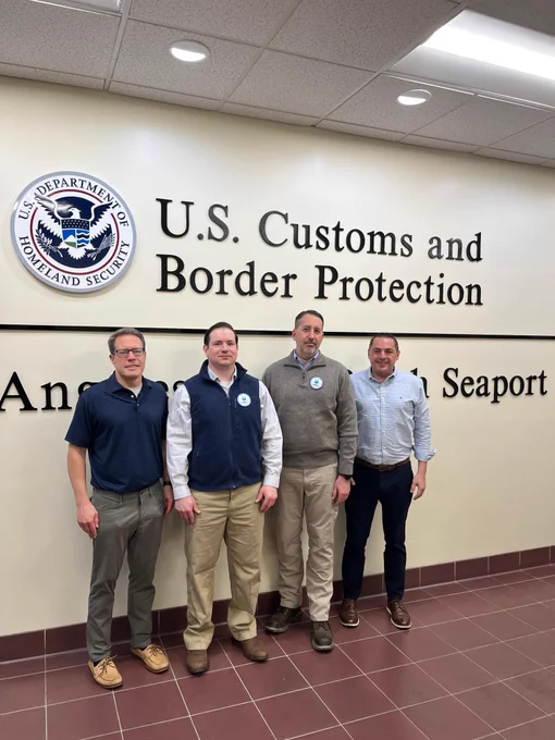 Four people standing in front of U.S. Customs and Border Protection sign at the Port of Los Angeles/Long Beach CBP examination warehouse.