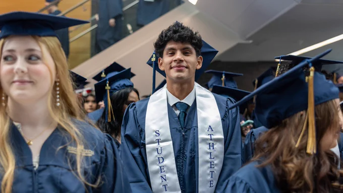 Male student athlete graduate in his cap and gown.