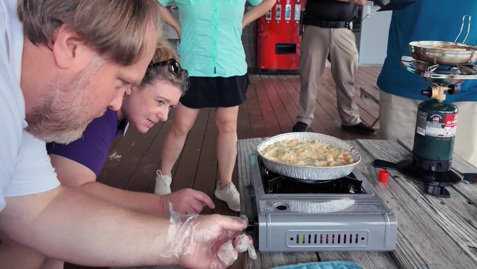 Mississippi-Alabama Sea Grant Resilience Engagement Lead Tracie Sempier, second from left, teaches Resilience Team Member Stephen Deal, left, and others to safely cook chicken pot pie using portable butane and propane stoves on July 24, 2025, at The University of Southern Mississippi Gulf Coast Research Lab in Ocean Springs, Mississippi. Photo by Melissa Schneider | Mississippi-Alabama Sea Grant.
