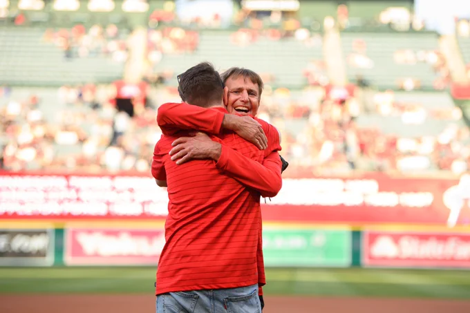 Angels Director of Field/Ground Maintenance Barney Lopas hugs his son, who caught his honorary first pitch, on the field before Friday's Angels-Rangers game at Angel Stadium. 
