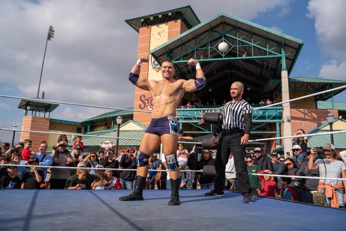 Independent professional wrestler and SoCal Pro Wrestling Heavyweight Champion Mathias flexing and posing with his championship title belt at the Lake Elsinore Storm Baseball Team Stadium; as seen on AEW, WWE Raw, TNA impact and MLW Major League Wrestling.