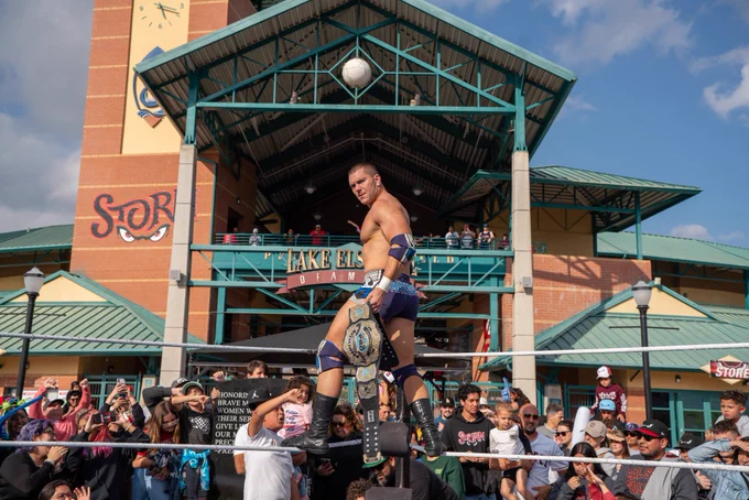 Independent professional wrestler and SoCal Pro Wrestling Heavyweight Champion Mathias flexing and posing with his championship title belt at the Lake Elsinore Storm Baseball Team Stadium; as seen on AEW, WWE Raw, TNA impact and MLW Major League Wrestling.
