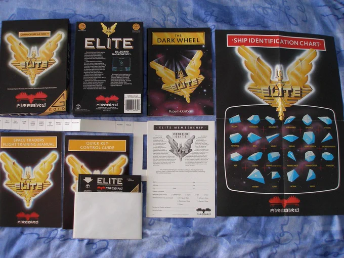 Commodore 64/128 Elite (Firebird, 1985) - box contents, comprising of the following (clockwise from top left):-
1. Retail box (front)
2. Retail box (back)
3. "The Dark Wheel" novella - Robert Holdstock (48 pages) 
4. Ship Identification Chart
5. Order Of Elite competition entry card
6. Game floppy disc - 5¼"
7. Quick Key Control Guide
8. Space Traders Flight Training manual (64 pages)
9. Keyboard overlay