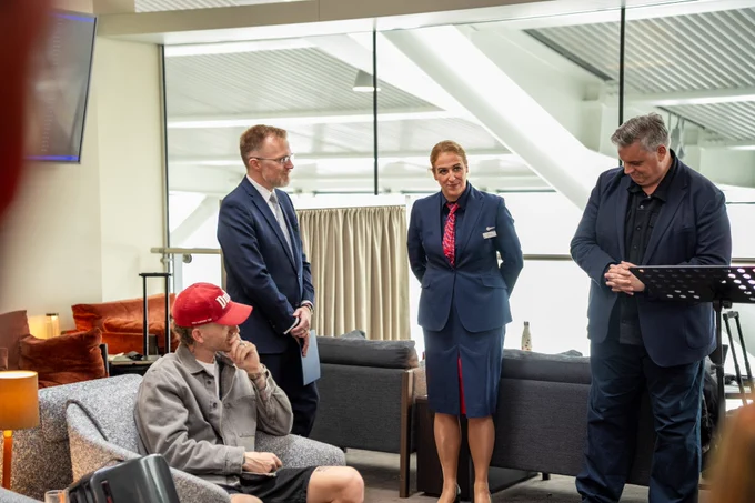 U.S. Deputy Chief of Mission Robert Thomas stands alongside fellow speakers in the airport lounge before they depart for L.A.